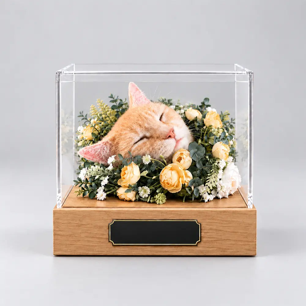 Handmade needle felted sleeping orange tabby cat replica nestled in floral decorations inside a protective acrylic shadow box.
